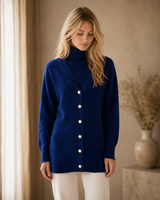 Woman wearing a navy blue cashmere long cardigan with white buttons indoors.