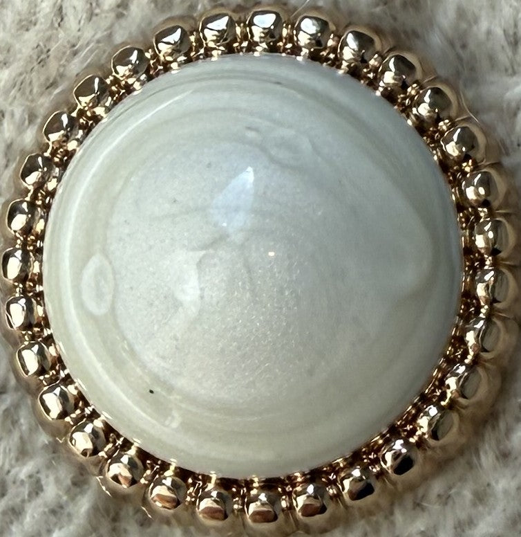 Pearl with a gold bead border on a textured surface