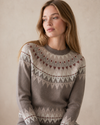 Woman wearing a patterned sweater against a beige background