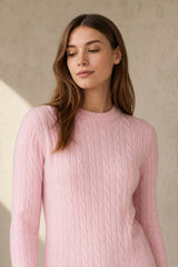 Woman wearing a pink ribbed cashmere sweater against a beige background
