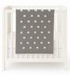 Gray baby blanket with white sheep pattern draped over a white crib.