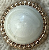Pearl with a gold bead border on a textured surface