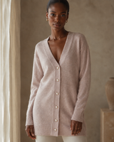 Woman wearing a light beige cashmerewool long cardigan in a neutral setting