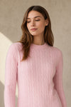 Woman wearing a pink ribbed cashmere sweater against a beige background