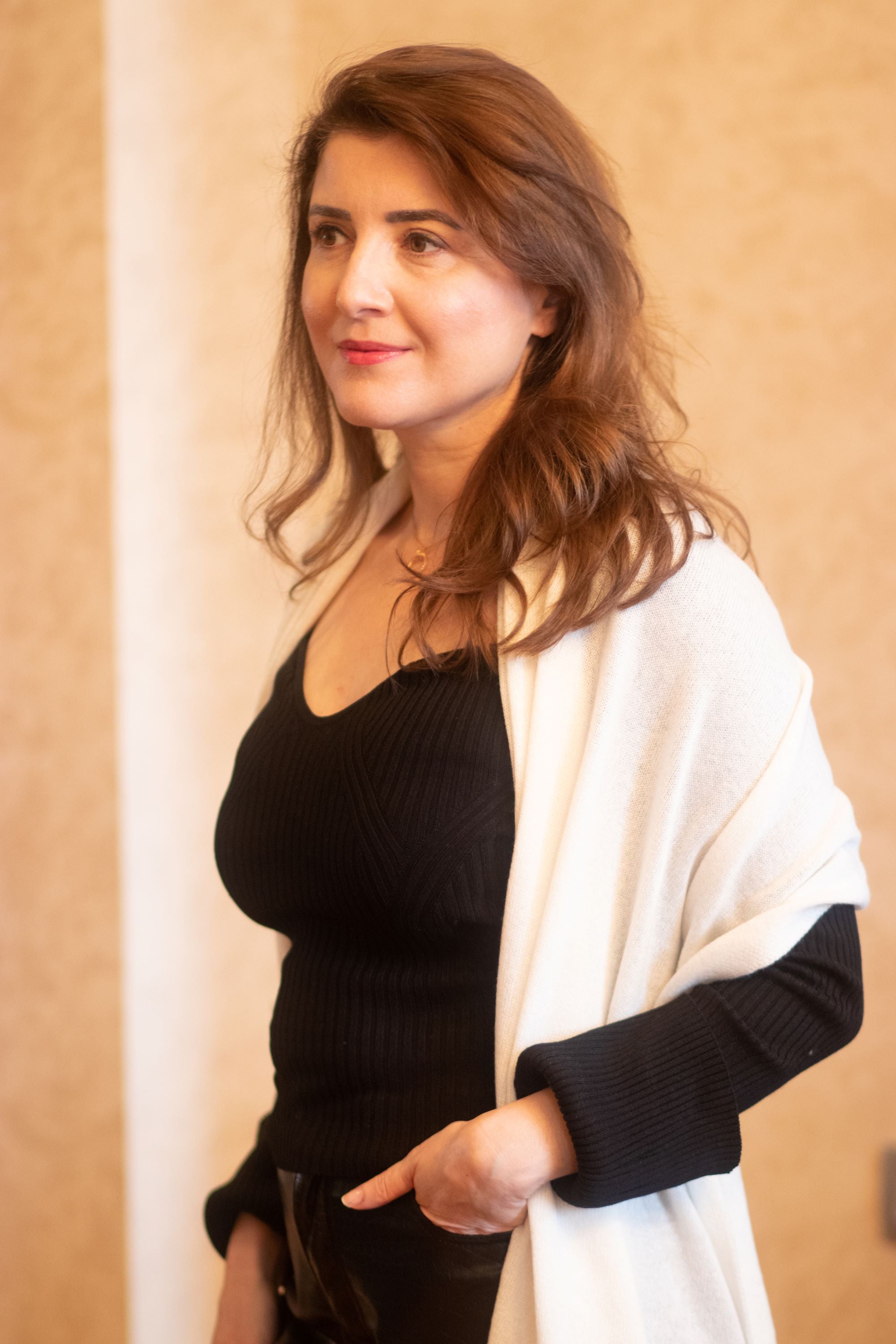 A woman wearing a black top and a white cashmere scarf with a neutral color.